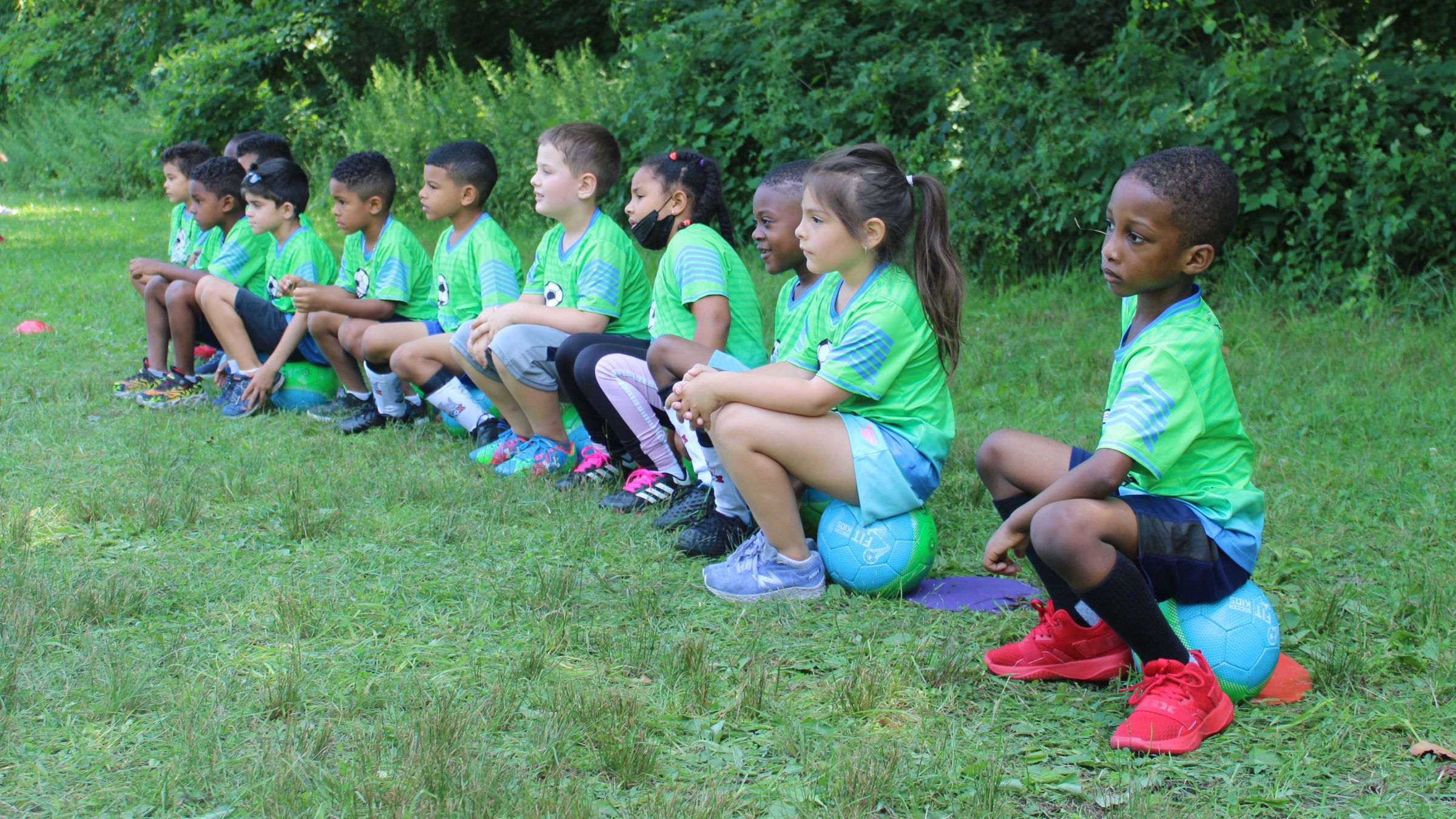 Coach leading a group of children through soccer drills at a Bronx park clinic