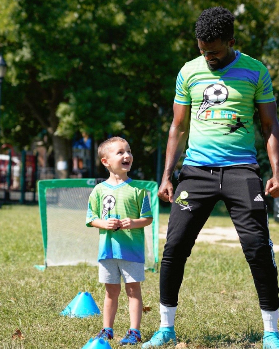 Fit Soccer Kids coaches engaging with a group of children seated on the grass during a session