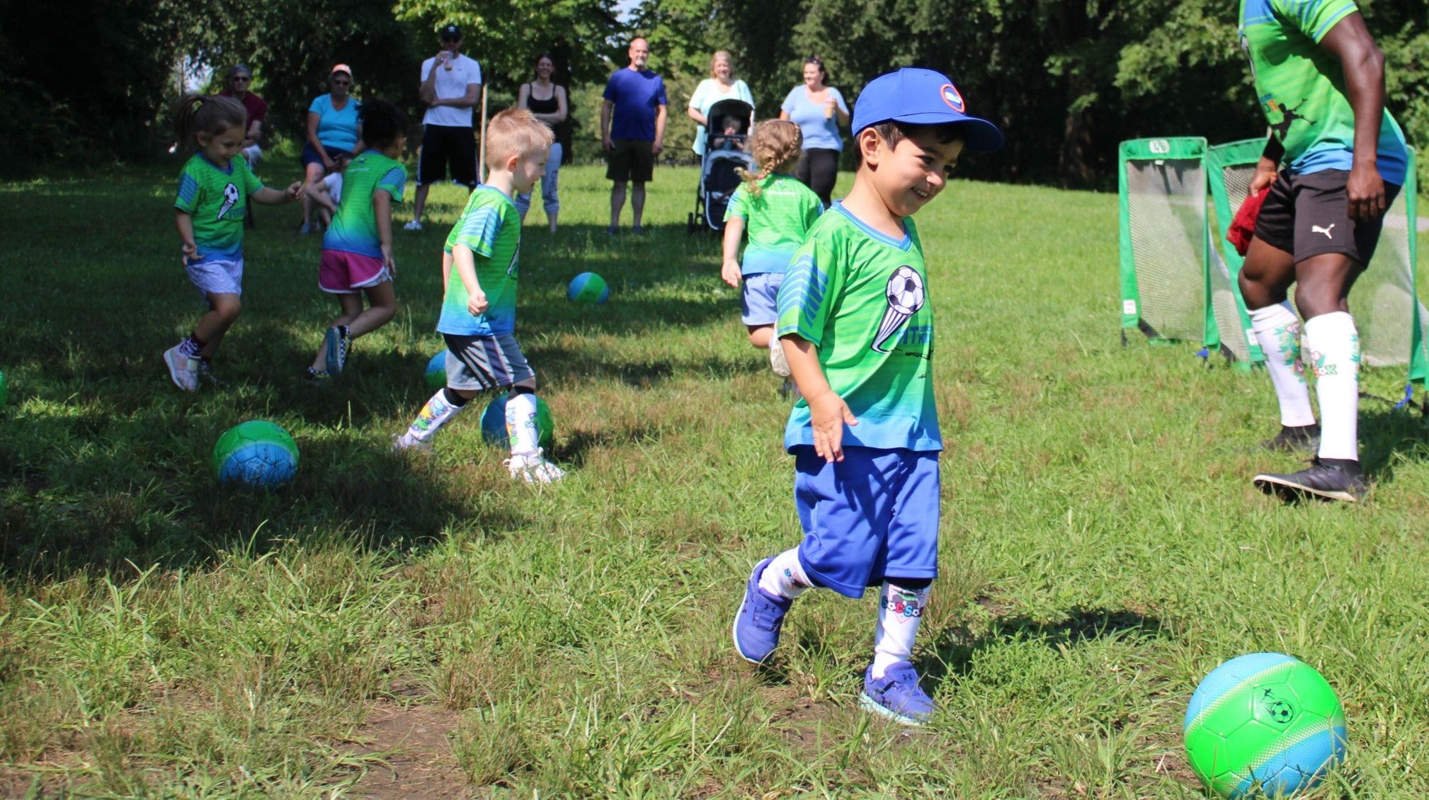 Small group of four children in green Fit Soccer Kids jerseys playing together outdoors